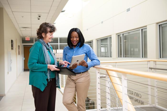 Two female professionals conferring about information on a computer tablet.