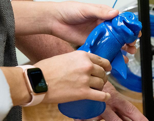 A student painting a mounted 3D print.